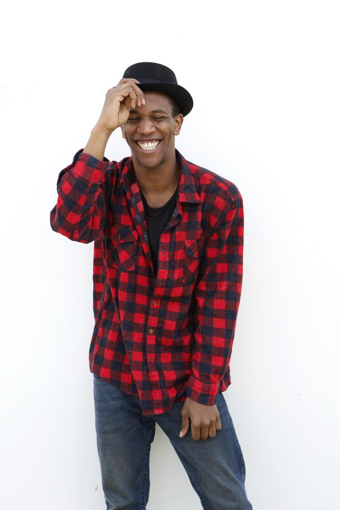 Portrait of a trendy young man laughing outdoors on white background