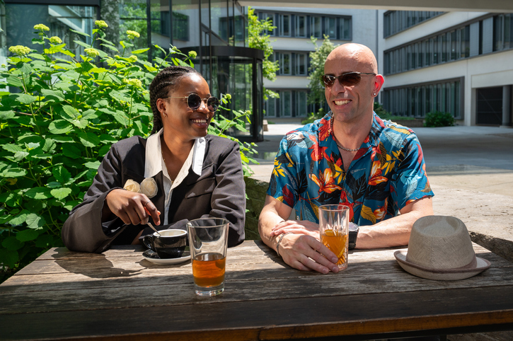 Medium shot of young woman and man enjoying a conversation at a bar table outside